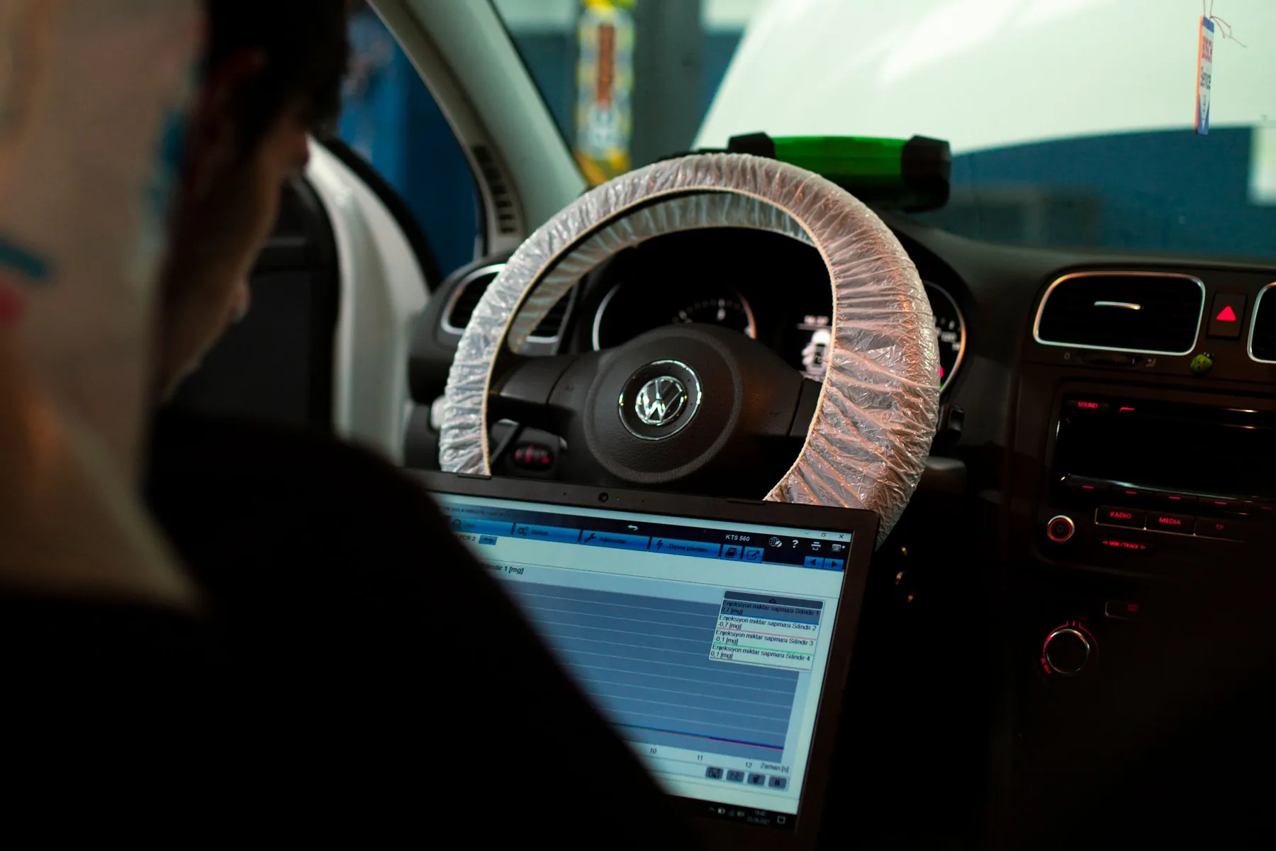 A laptop plugged into a car in the workshop, reading the engine software